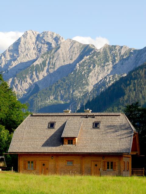 Dřevěná budova chaty Hengstpass v pozadí skalnaté horské kulisy