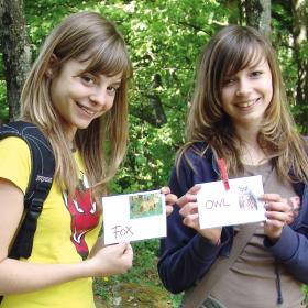 Dvě dívky drží karty zvířat s anglickými popisky