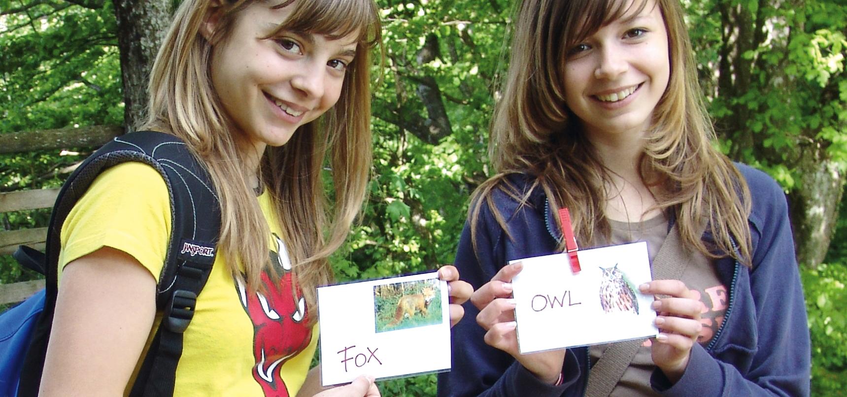 Dvě dívky drží karty zvířat s anglickými popisky