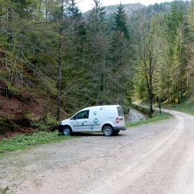 Auto zaparkované na štěrkovém parkovišti v zalesněné oblasti