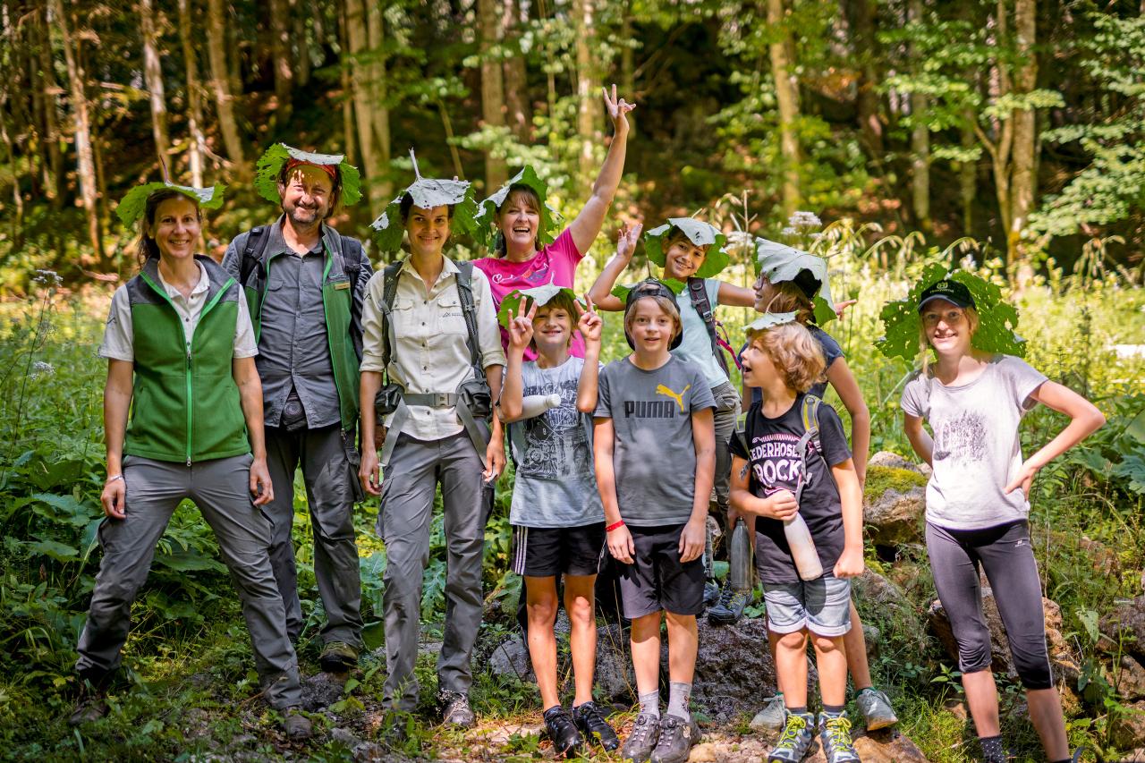 Skupina dětí se strážcem národního parku používající velké listy jako sluneční klobouk