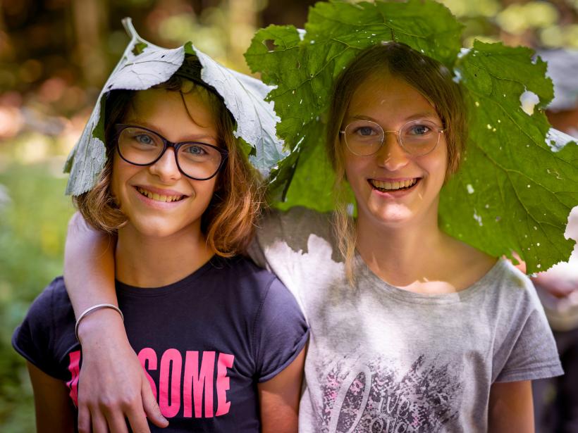 Dvě dívky si na hlavu nasadily velký list podbělu.
