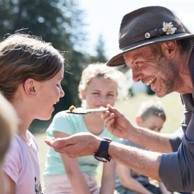 Strážce národního parku podává dívce jídlo na dřevěné lžíci