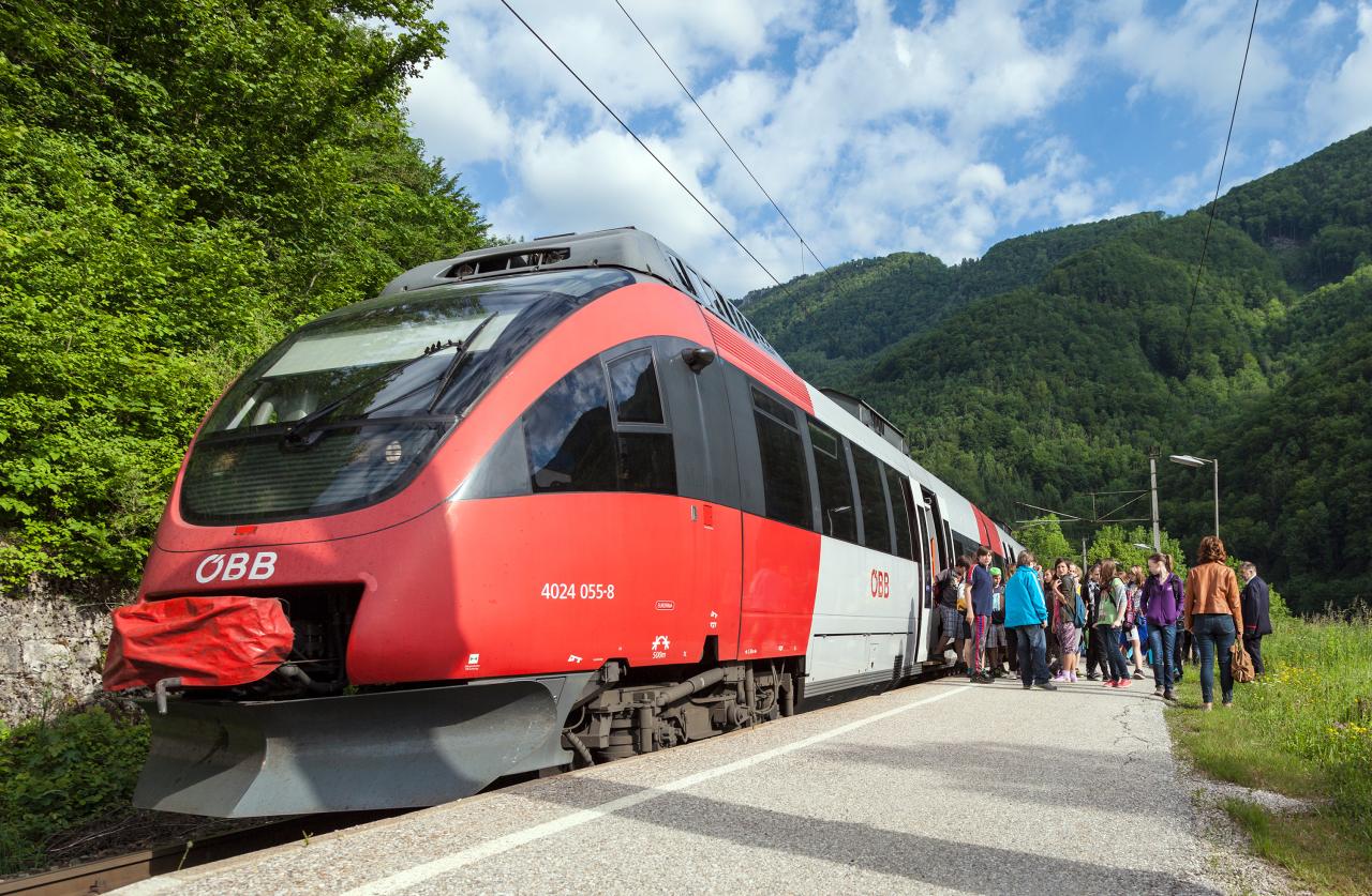 Lidé vystupují z vlaku a shromažďují se na nástupišti.