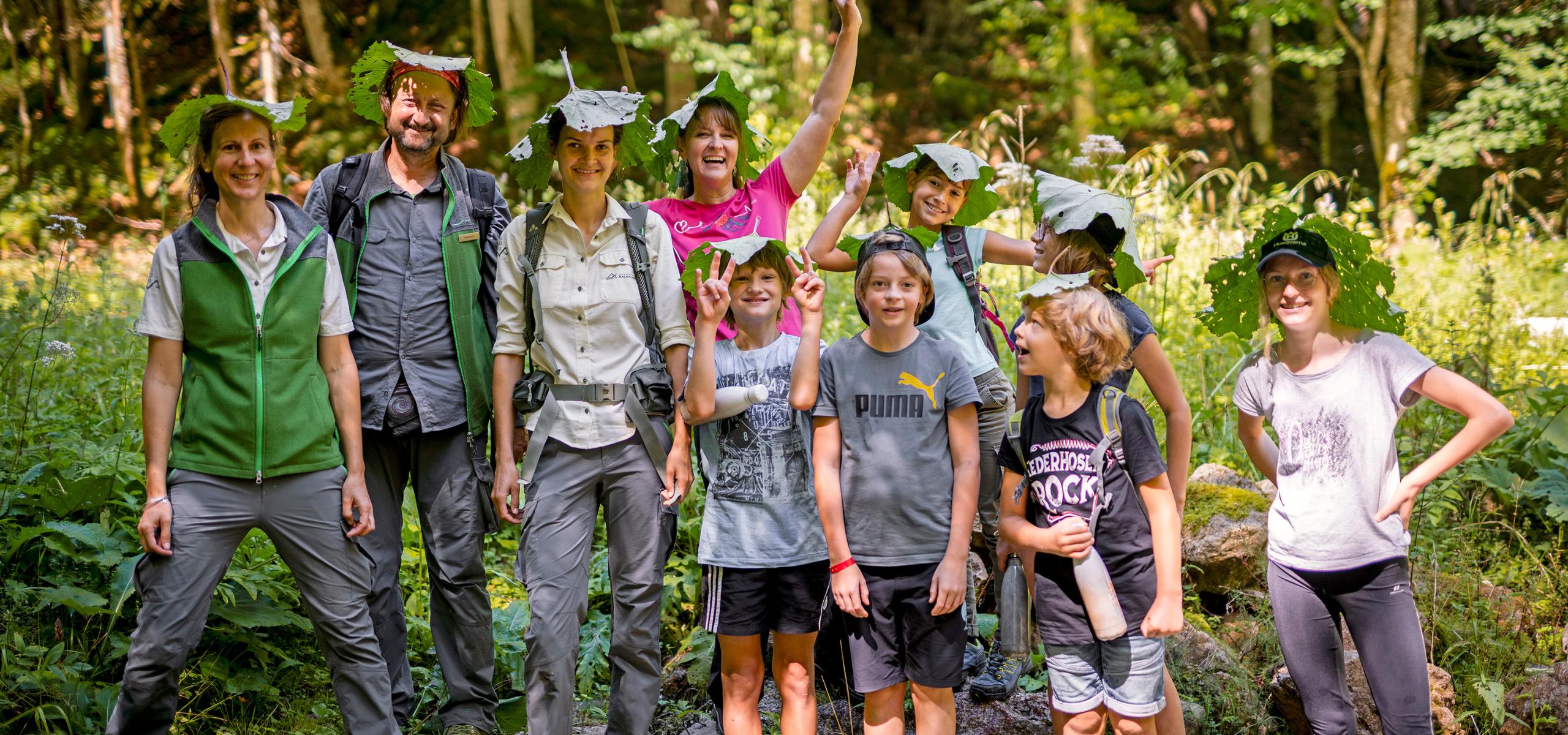 Skupina dětí se strážcem národního parku používající velké listy jako sluneční klobouk